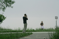 Boy photographing girlfriend on foggy day.